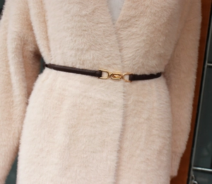 Close-up of thin dark brown leather belt with gold metal buckle on beige cardigan