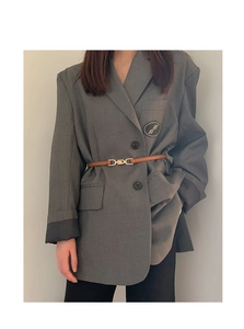 Detail showing a slim brown leather belt with gold buckle styling on a grey blazer jacket
