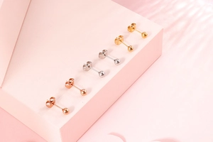 Nahaufnahme von Kugelohrsteckern in Gold, Silber und Roségold auf einem Display