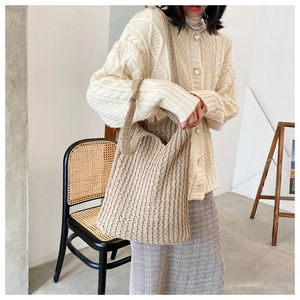 Modelo con un gran bolso tote tejido beige en un ambiente interior minimalista con luz