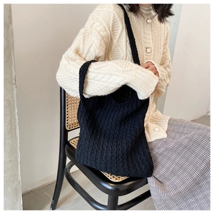 Primer plano del bolso tote de punto negro con textura de material suave y tejido