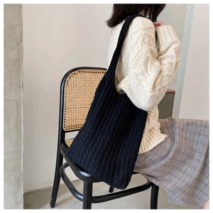 Detalle del bolso tote tejido negro con textura de punto y correa al hombro