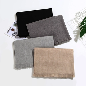 Detailed view of four solid cashmere-feel scarves with neat fringe in neutral winter tones
