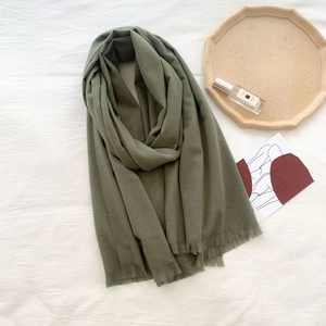Close-up of olive green cashmere scarf with fine tassels on white fabric background