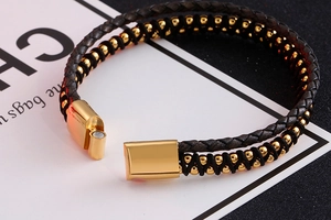 Detail of double-layer braided leather bracelet with golden metal beads and magnetic clasp