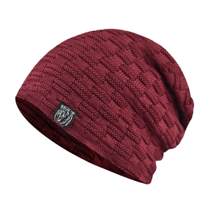 Close-up of wine red chenille knit beanie with thick textured pattern and wolf logo patch
