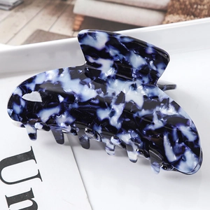Detailed view of hair claw clip with dark blue marble texture and acetate material finish