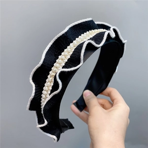 Detailed macro view of knitted black ruffle headband with white faux pearls decoration