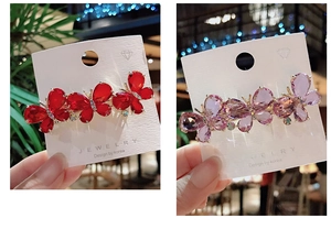 Detailed close-up of crystal butterfly hair clips in vibrant red and purple colors