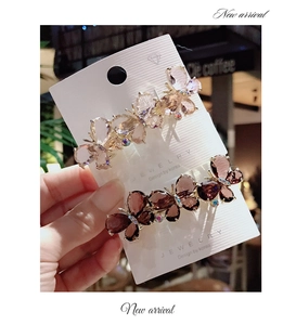 Detail view of crystal butterfly hair clips in champagne and purple on jewelry card