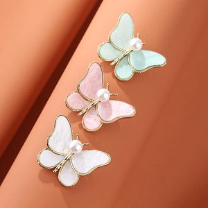 Detailed macro view of butterfly brooches with pearlescent wings and central pearl accents