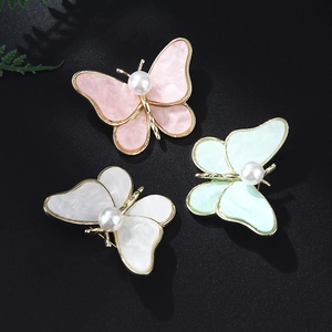 Detailed view of alloy butterfly brooches with marble resin wings and white pearls