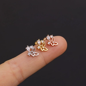 Macro shot of three small butterfly stud earrings in silver, gold, and rose gold finishes