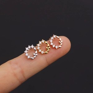 Detail of floral zircon earrings in silver, gold, and rose gold on a hand for scale
