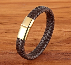 Detail of brown braided leather bracelet featuring a golden magnetic clasp on wood
