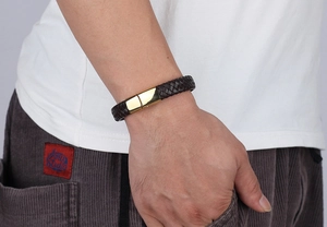 Detail of brown braided leather bracelet featuring a polished gold metal clasp on wrist