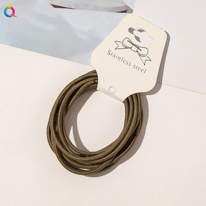 Close-up of olive green elastic hair ties bundled on a white retail hanging card