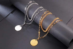 Detailed view of layered stainless steel chains with blank round pendants in gold and silver