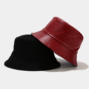 Detail of red faux leather and black canvas bucket hats showing material texture and stitching
