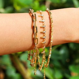 Close-up of gold paperclip chain and triangle pendant bracelets with pavé zircons