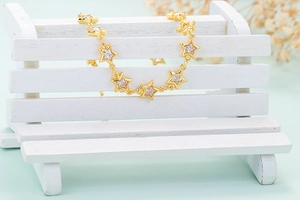 Detailed shot of star-shaped gold chain with cubic zirconia on a white mini bench