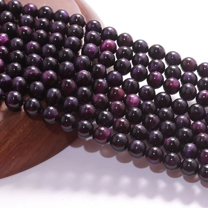 Polished purple tiger eye stone beads on a wooden base for DIY jewelry making