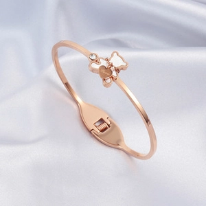 Rose gold bear charm bracelet with Love engraving displayed on soft silver silk