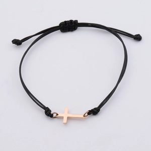 Vue macro du bracelet tressé noir réglable avec pendentif croix en or rose poli