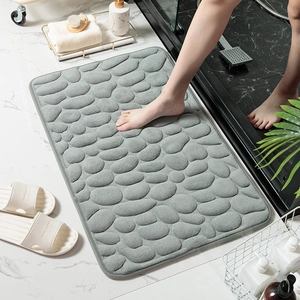 Vista detallada de alfombra de baño con diseño de guijarros grises, suave y absorbente.