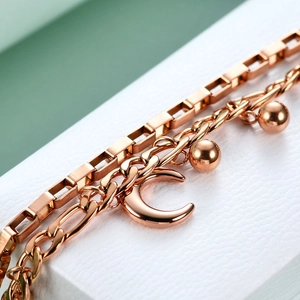 Macro detail of rose gold double-layer Cuban chain with polished moon and ball charms