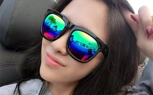 Detail of square black sunglasses with colorful rainbow mirrored lenses worn in a car