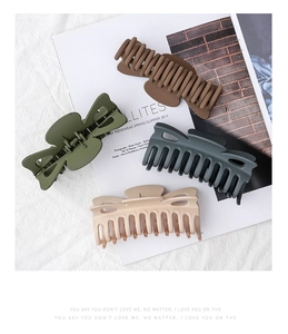 Matte finish large hair claws in olive green, brown, grey, and pink on a magazine