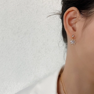 Close-up of elegant gold heart stud earring with sparkling zircon on model ear