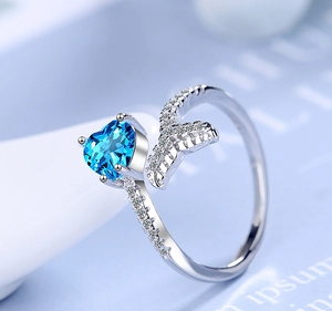 Macro shot of silver ring featuring a blue heart gemstone and diamond mermaid tail detail