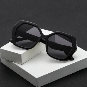 Chic oversized hexagonal black sunglasses with thick frames on a modern white geometric base