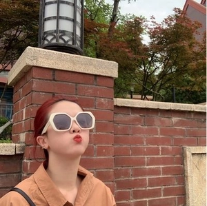 Outdoor lifestyle shot of oversized beige geometric sunglasses with dark grey lenses
