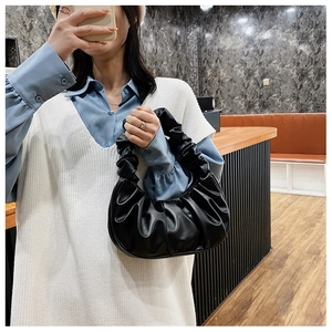 Detail of a black pleated cloud bag with soft synthetic leather and a stylish shoulder strap