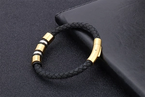 Detail of black braided leather bracelet with gold and silver beads and magnetic clasp