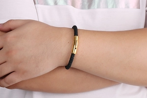 Close-up of black braided leather bracelet with golden magnetic clasp on male wrist