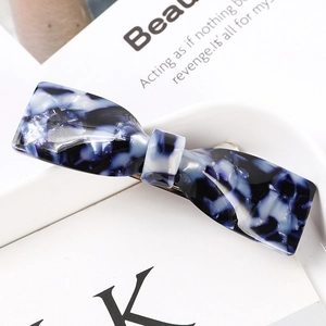 Detail of blue marble acetate hair claw clip with bow shape and metal clamp mechanism