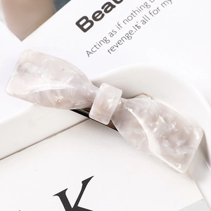 Close-up of elegant marble pattern acetate bow hair clip on a white decorative tray