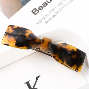 Detail view of acetate tortoise shell hair claw clip with elegant bow design and metal spring