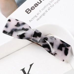 Macro detail of a bow-shaped acetate hair claw with black and white marble texture