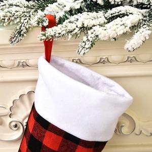 Detail of red and black buffalo plaid Christmas stocking with white plush cuff on tree