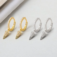 Detail view of gold and silver hoop earrings with pave cubic zirconia and cone pendants