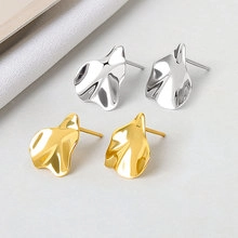 Detail showing minimalist irregular wave stud earrings in polished gold and silver finish