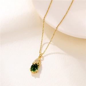 Close-up of a golden Pixiu pendant with a green bead on a delicate necklace chain