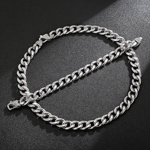 Macro shot of silver Cuban chain links with polished finish on a black textured background