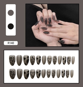 Detail view of almond shaped matte press-on nails with heart graffiti in grey and black