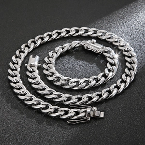 Silver Cuban link chain necklace and bracelet set displayed on a dark textured surface
